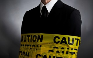 businessman wrapped up in yellow and black caution tape