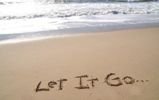 Words "Let it Go" written in sand