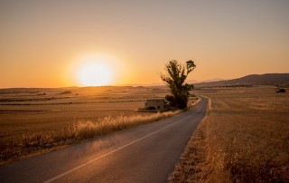 empty road heading west into a fading sunset