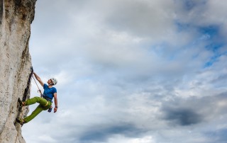 solo mountain climber heading up face of cliff