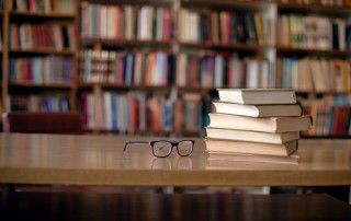 image of library books on table with pair of eyeglasses next to them