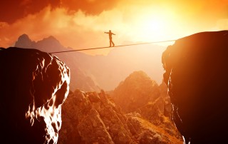 Image of person on a tightrope stretched between two cliffs